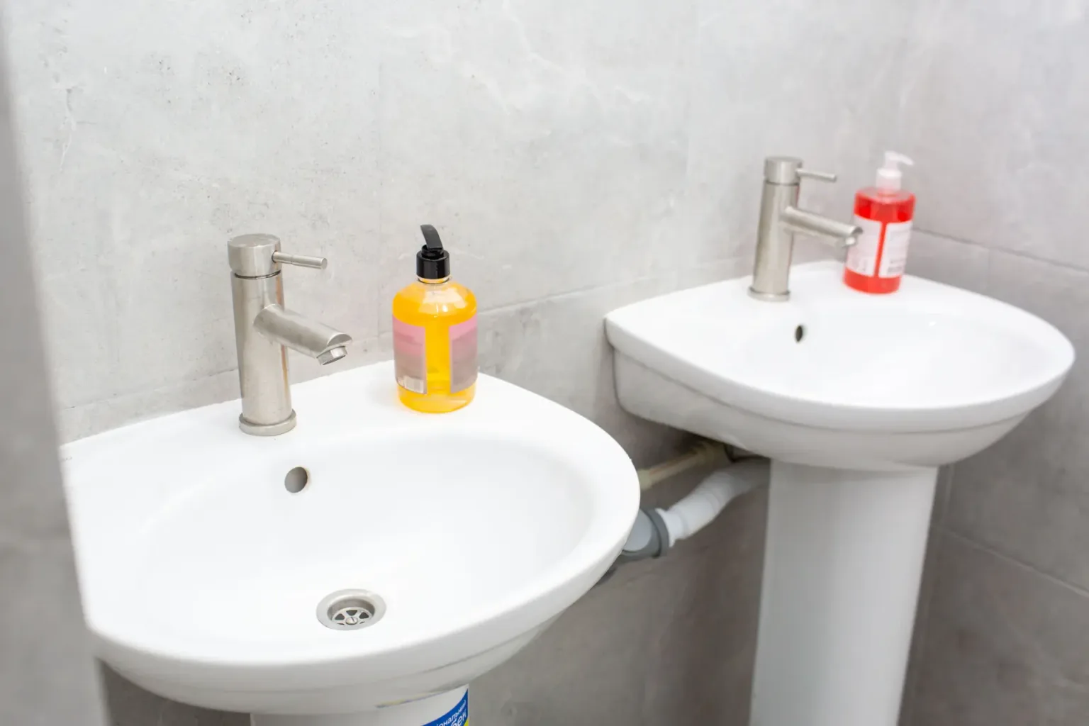 Два умивальники з рідким милом у ванній кімнаті