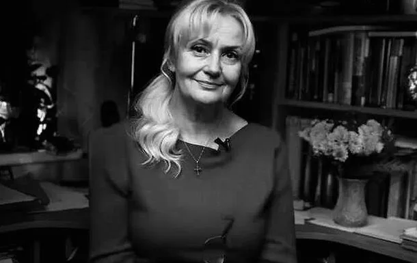 Жінка з посмішкою сидить у кімнаті з книжками