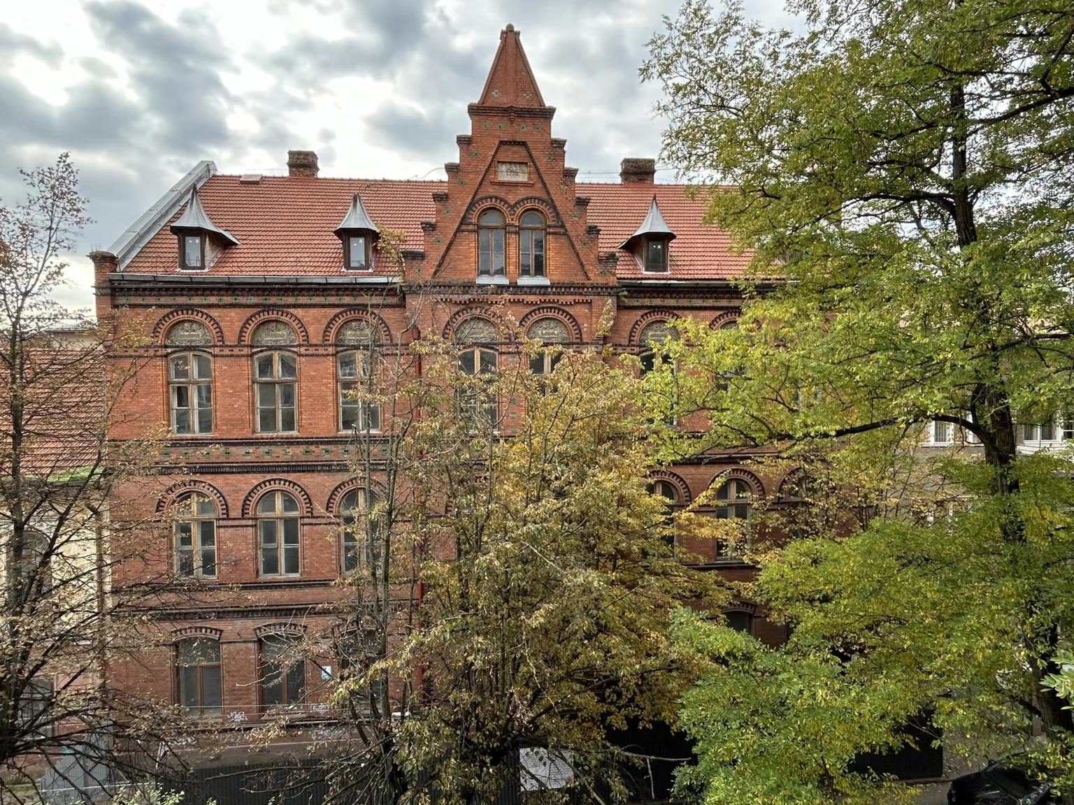 Старовинна цегляна будівля серед осінніх дерев