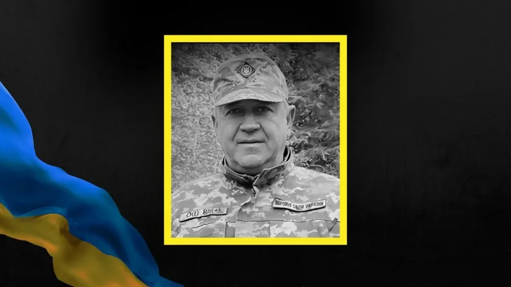 Український військовослужбовець у камуфляжі на тлі прапора