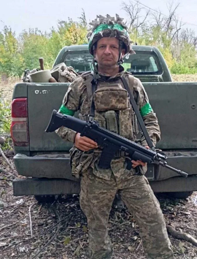 Український військовий із зброєю біля вантажівки