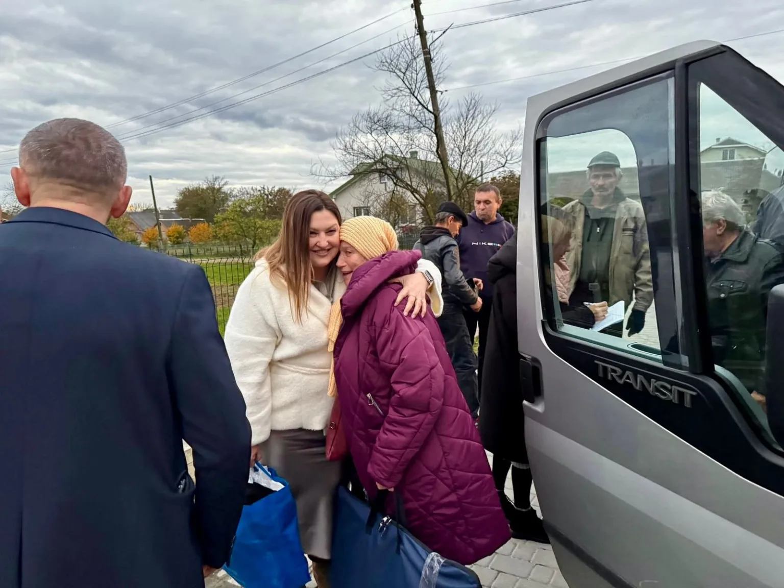 Люди обіймаються біля мікроавтобуса у селі
