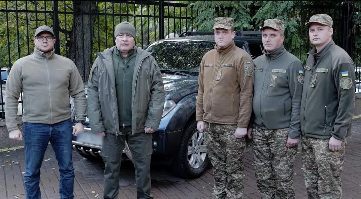 Військові стоять перед автомобілем на вулиці