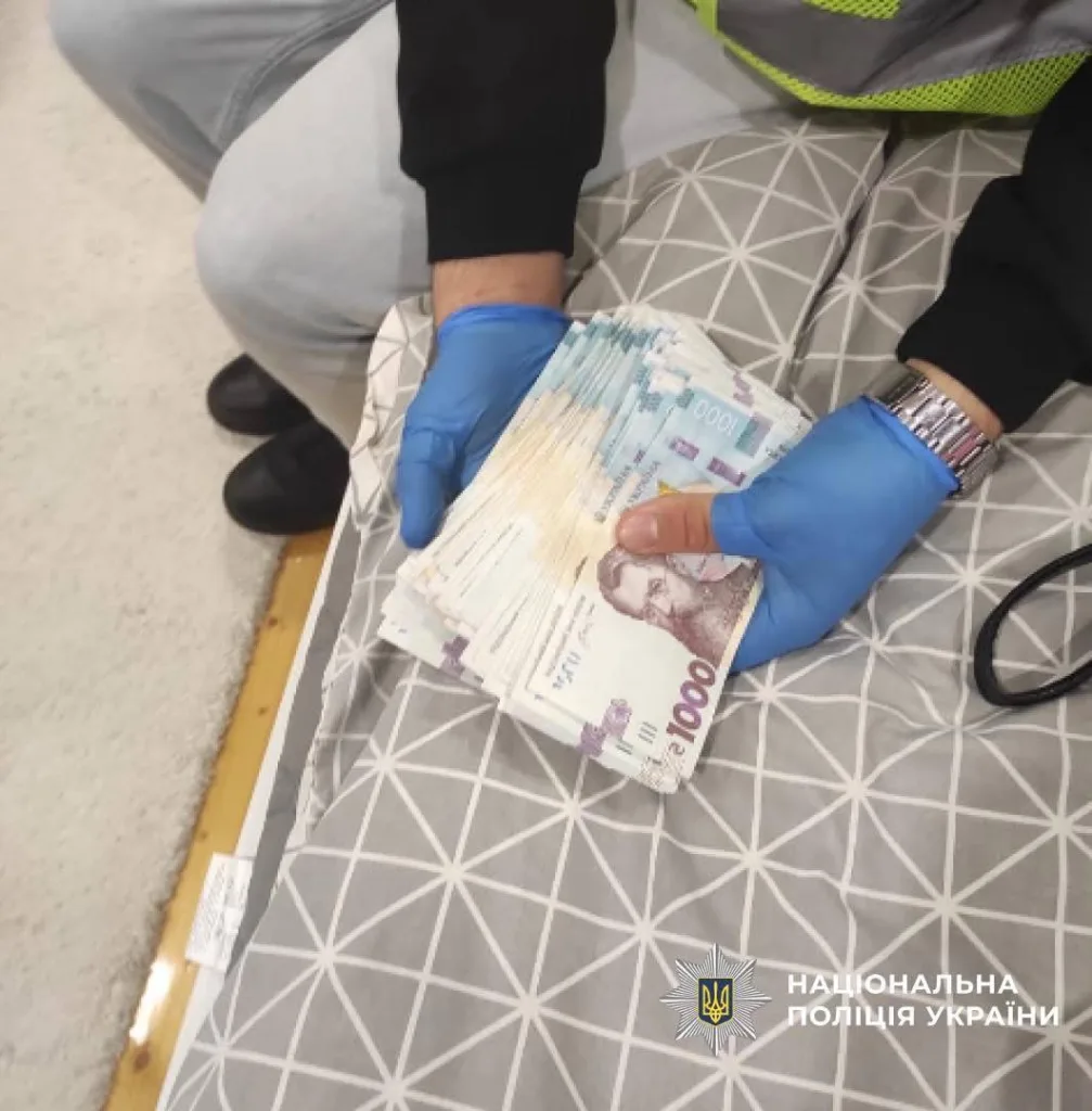 Поліція тримає гроші під час обшуку