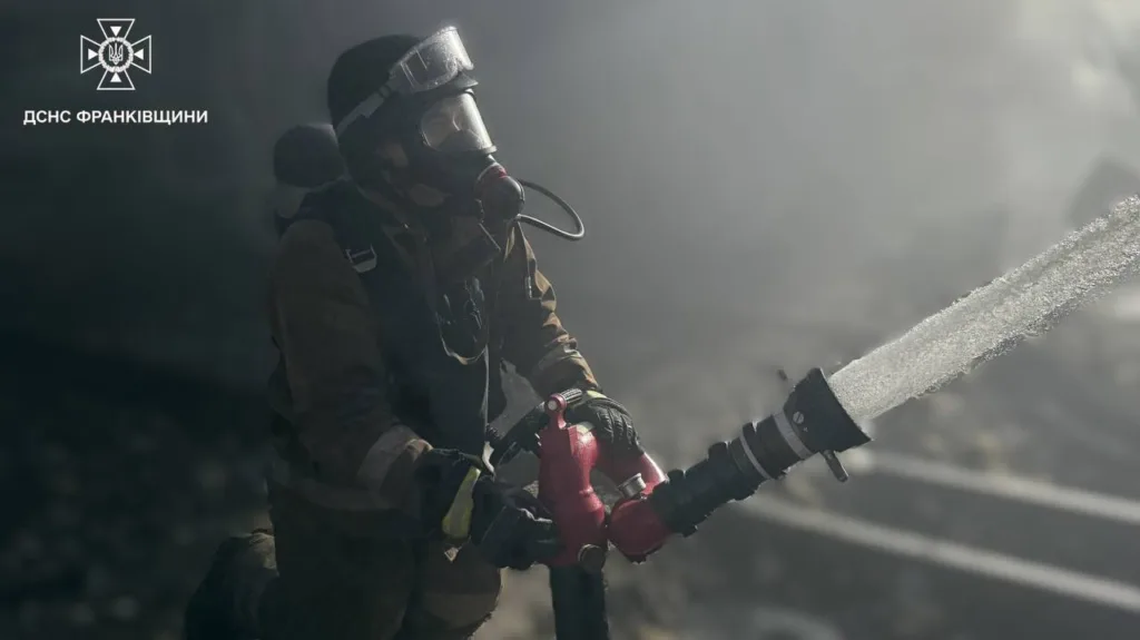 Пожежник гасить вогонь водяним шлангом