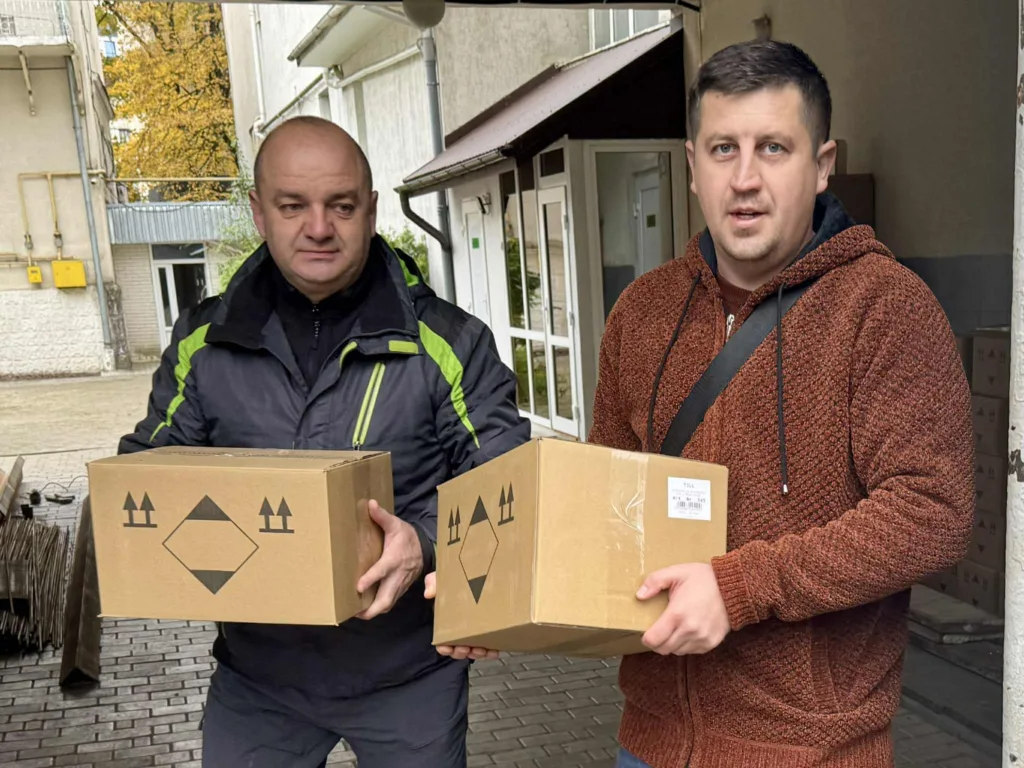 Чоловіки тримають картонні коробки біля будівлі