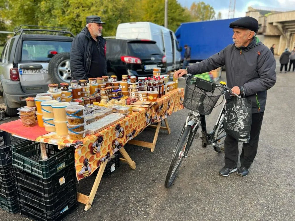 Чоловік купує мед на сільському ринку
