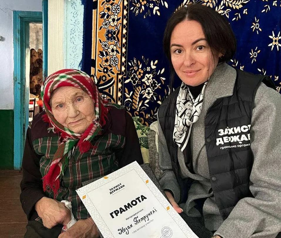 Жінка отримує грамоту від представниці організації