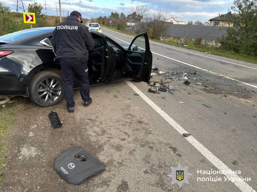 ДТП, поліцейський оглядає пошкоджене авто на дорозі