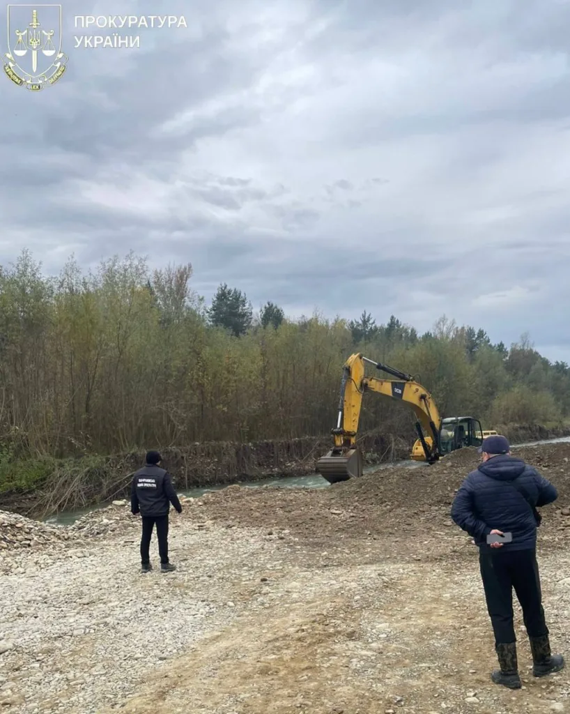 Екскаватор працює біля річки під наглядом працівників