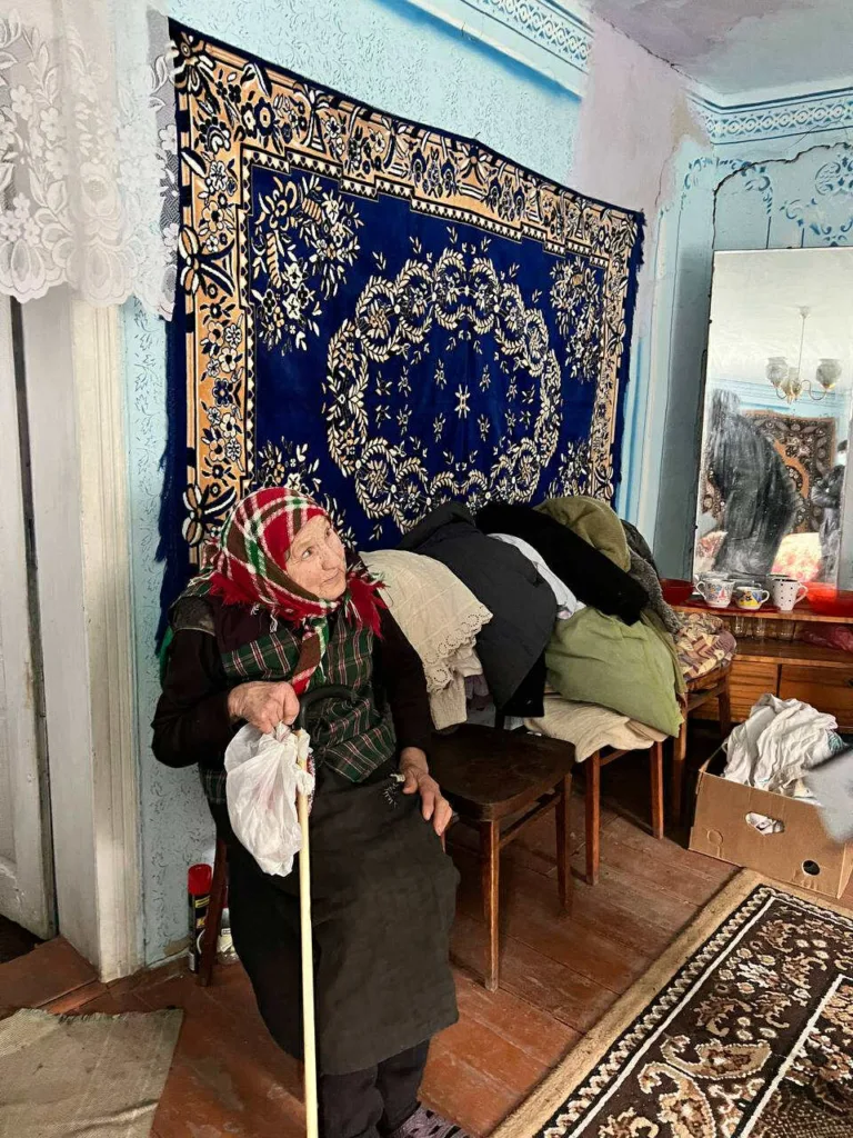Літня жінка сидить у кімнаті з килимом