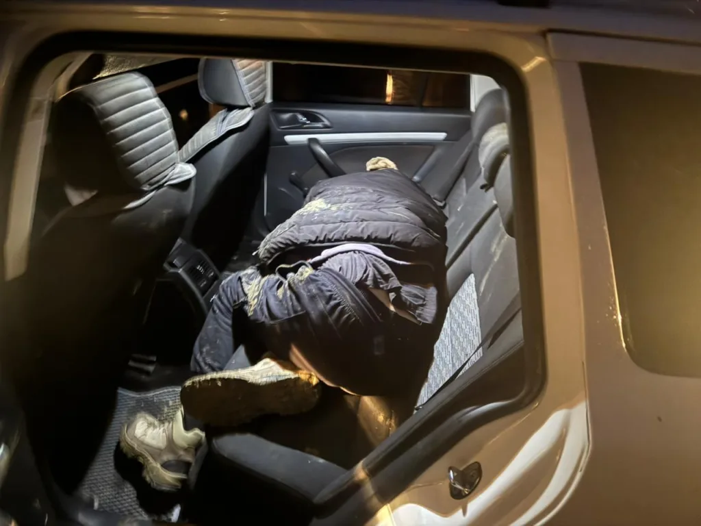 Людина спить у автомобілі на задньому сидінні.