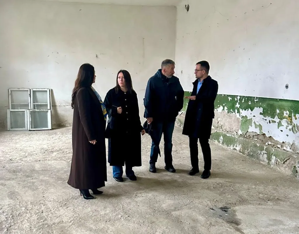 Люди оглядають стару будівлю з облущеними стінами