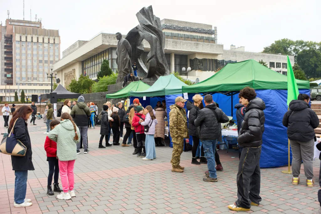 Люди на ярмарку біля пам'ятника та наметів