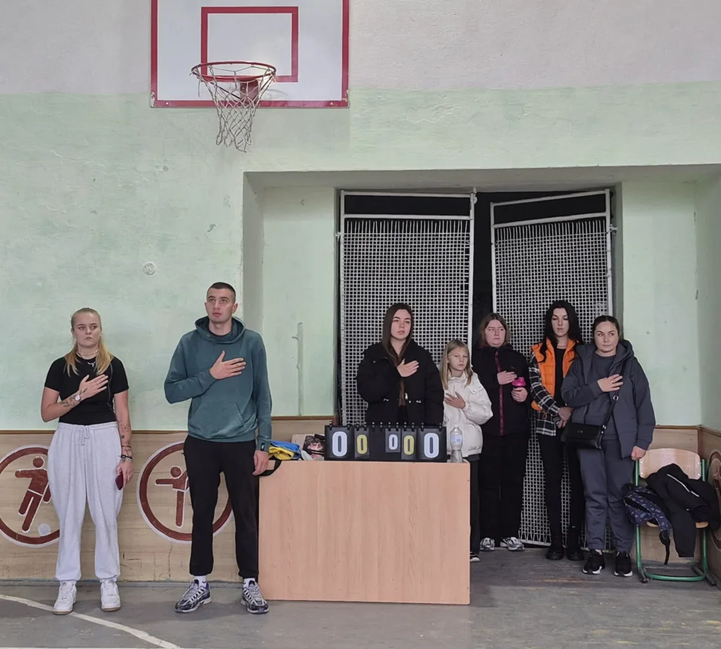 Люди стоять у спортзалі з рукою на серці