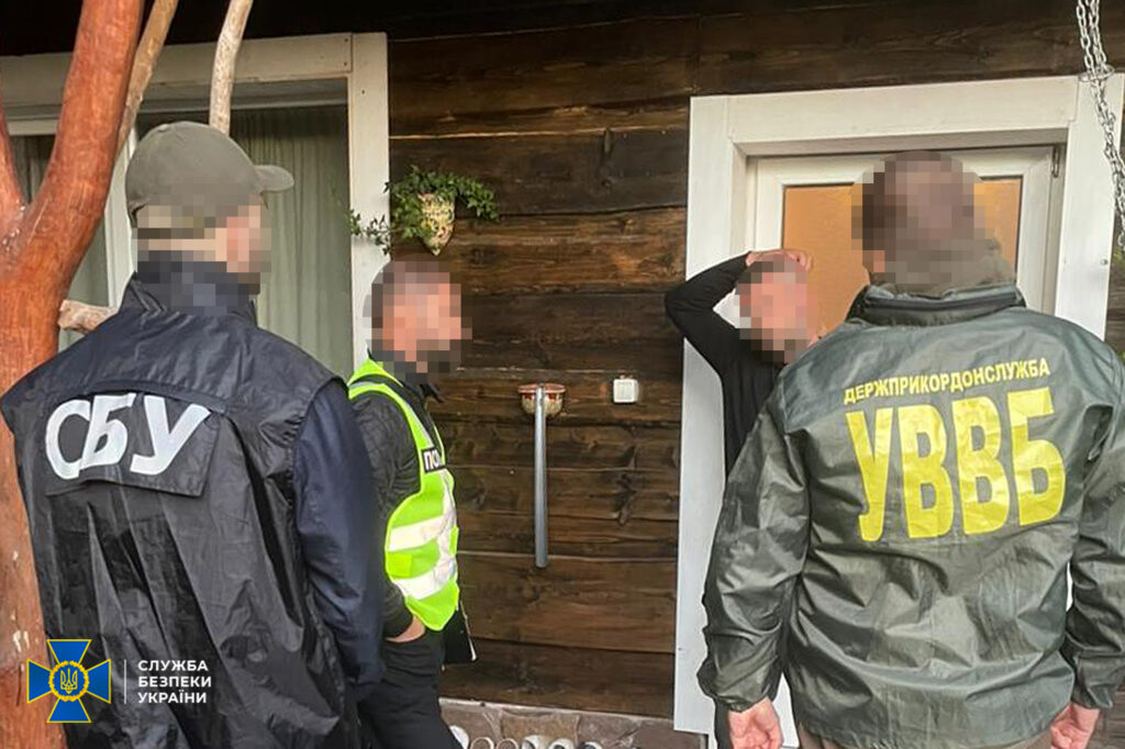 Офіцери СБУ розмовляють з чоловіком біля будинку.