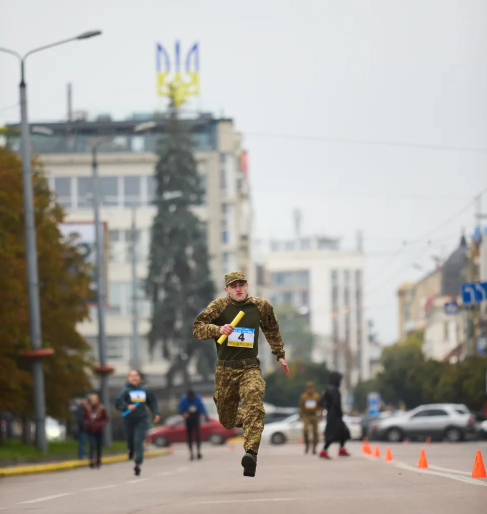 Військовий біжить під час змагань у місті.