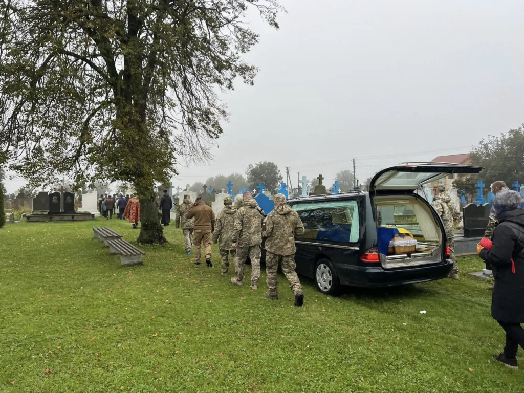 Військовий похорон на кладовищі під дощем.