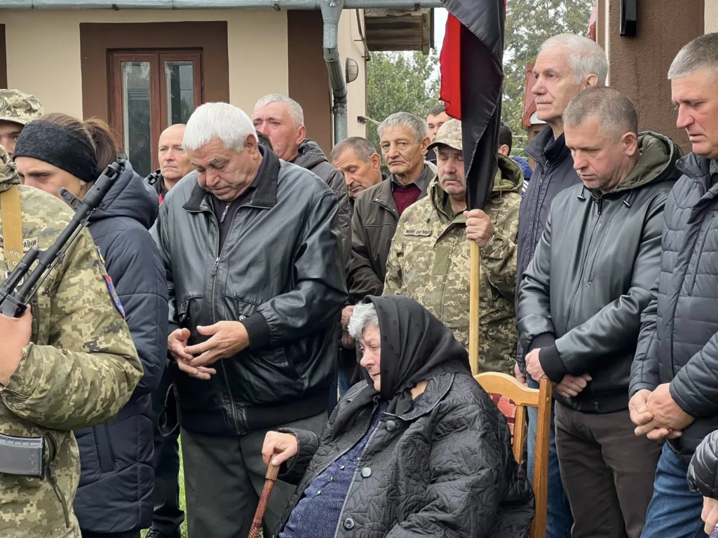 Група людей на церемонії з символами України.