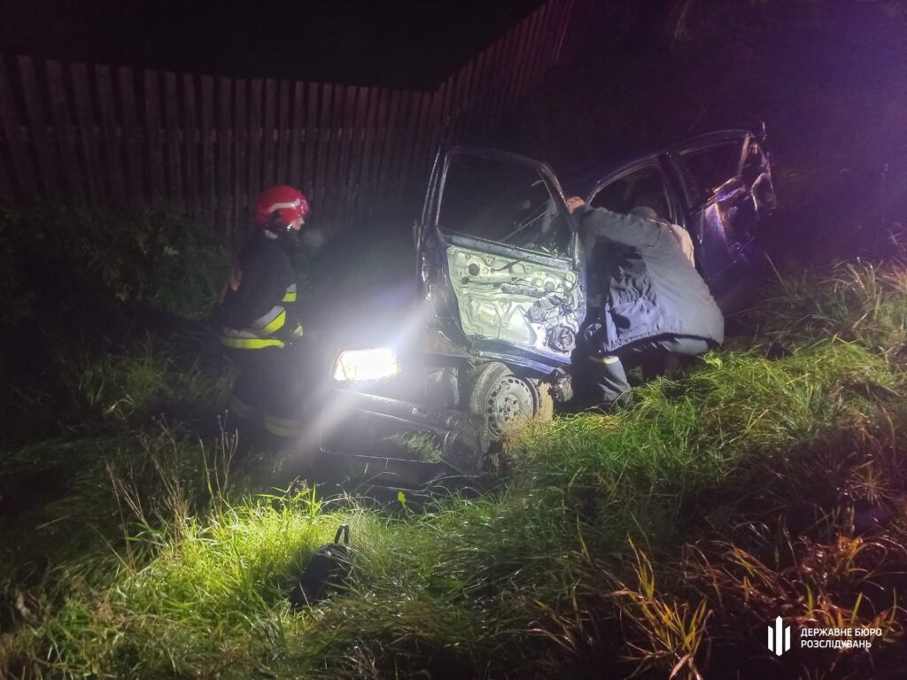 Пожежники допомагають при аварії автомобіля вночі.