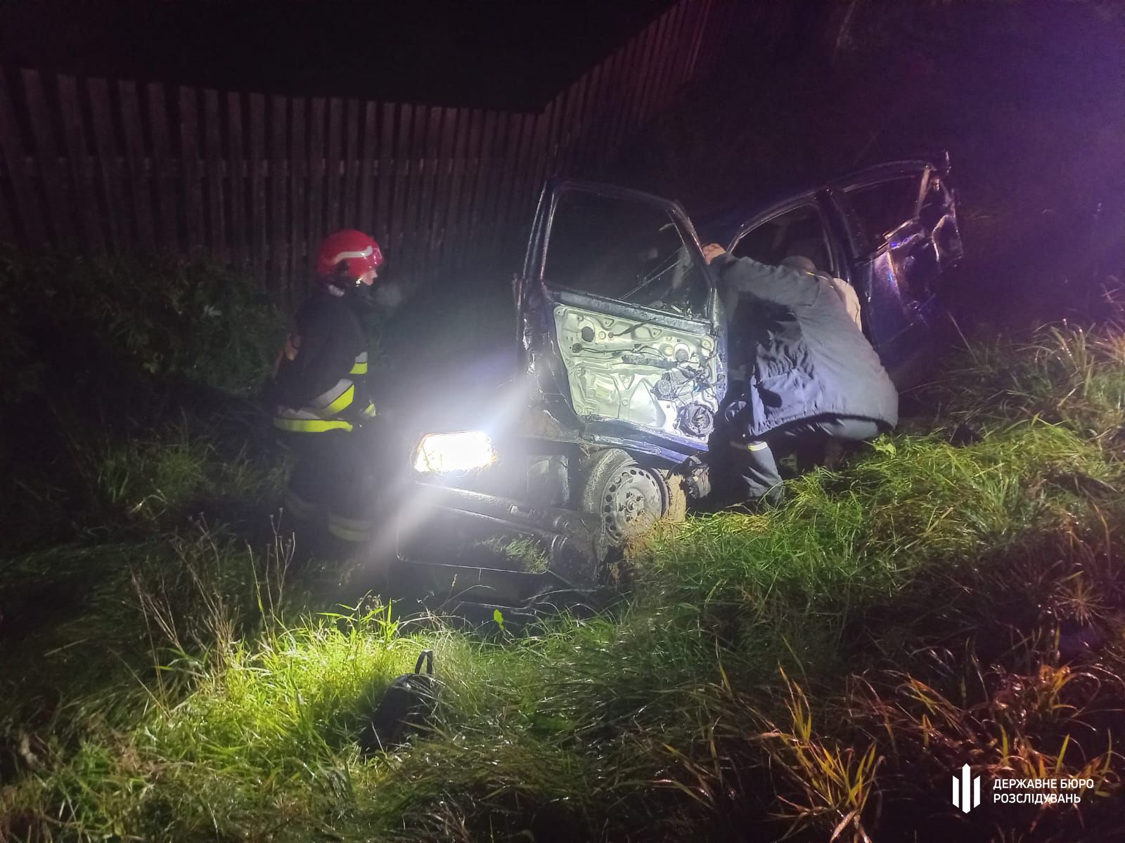 Пожежники допомагають при аварії автомобіля вночі.