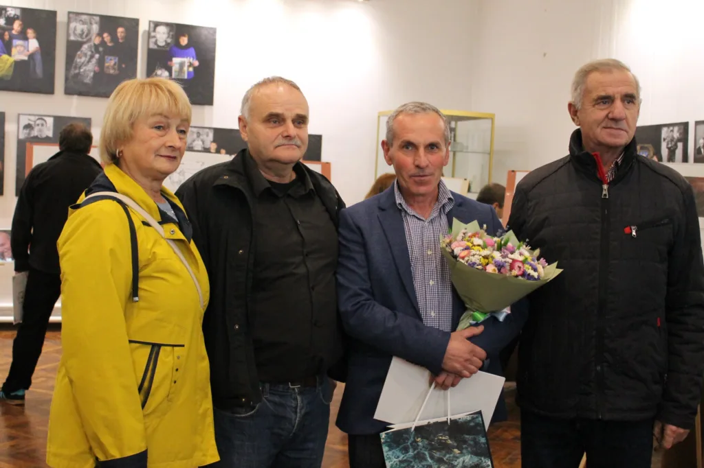 Люди стоять у художній галереї з квітами
