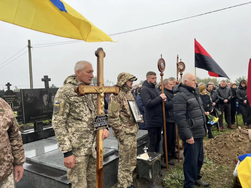 Церемонія вшанування з українськими прапорами на кладовищі.