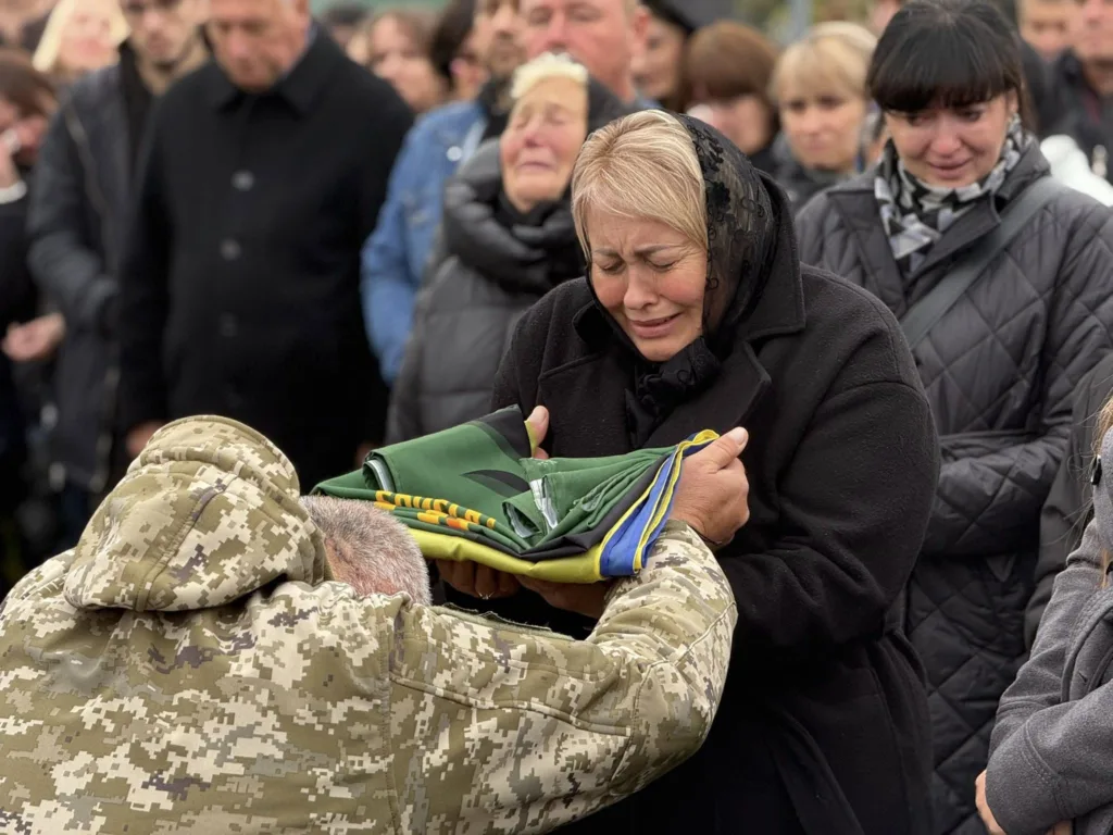 Похорон військового, жінка тримає складений прапор України