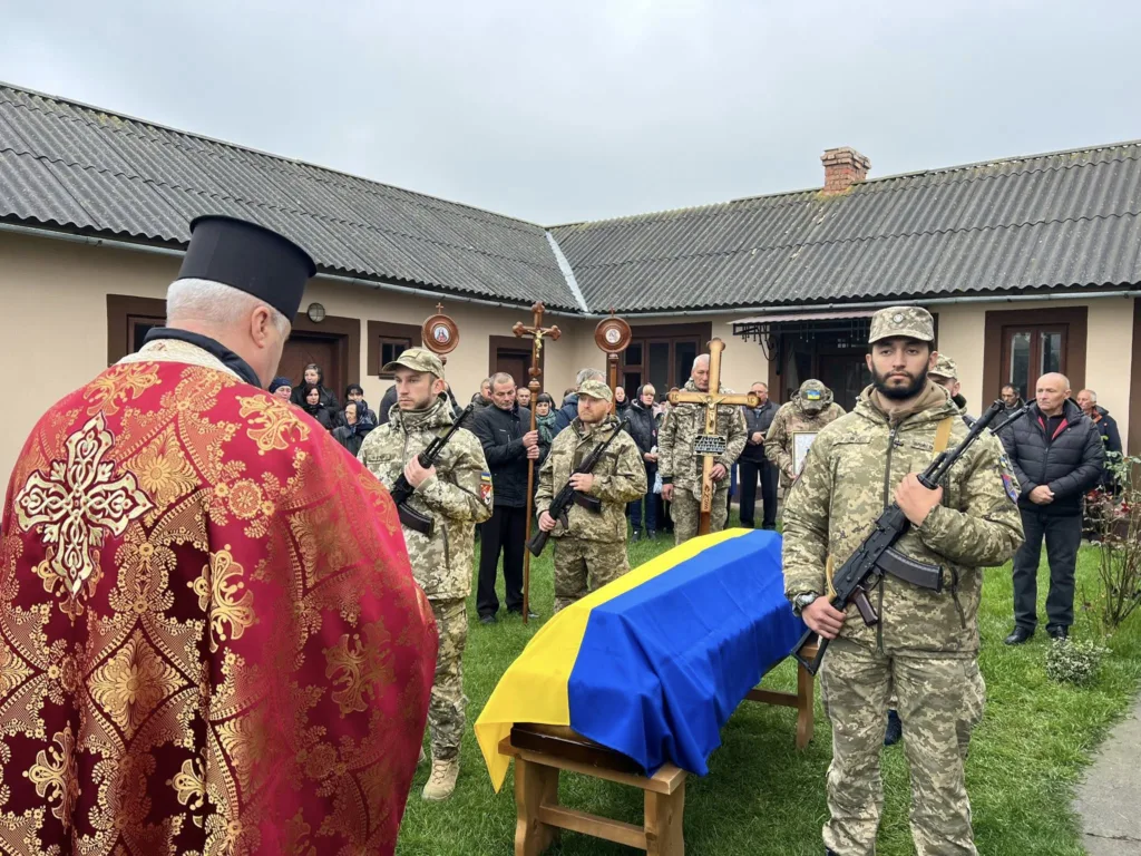 Військова почесна варта біля труни під прапором.