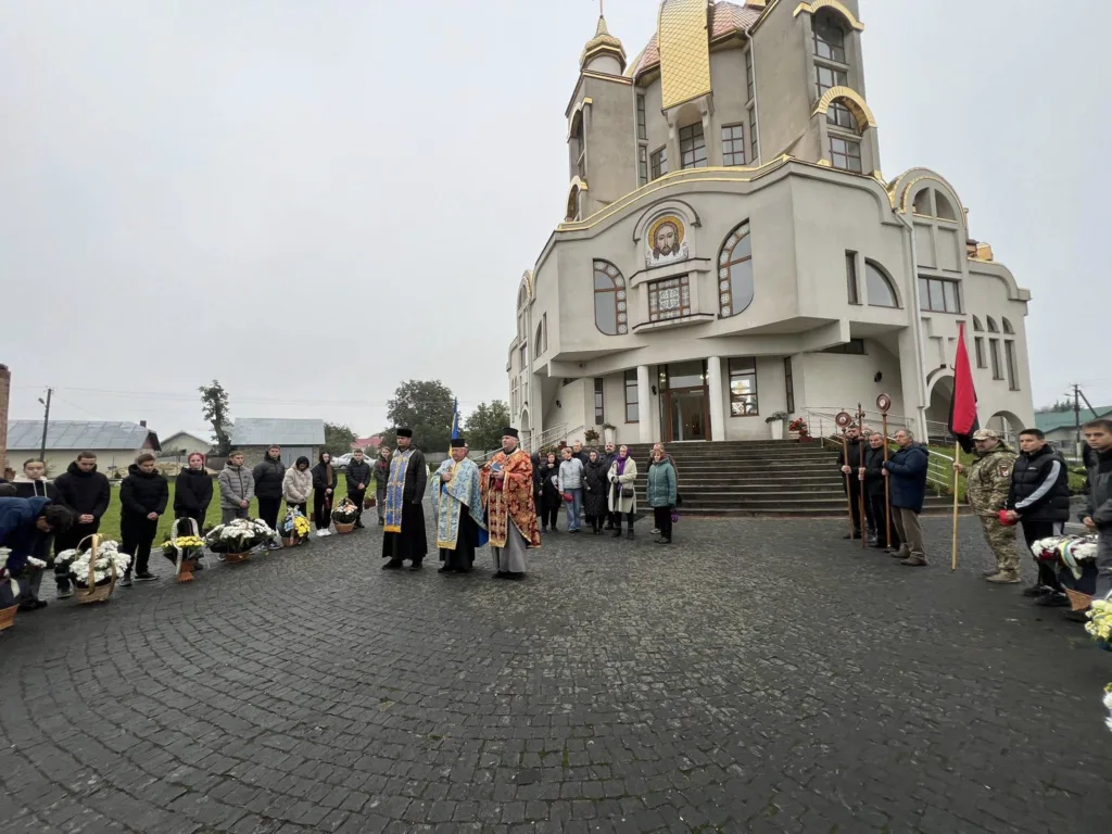Люди перед церквою на церемонії з прапорами.