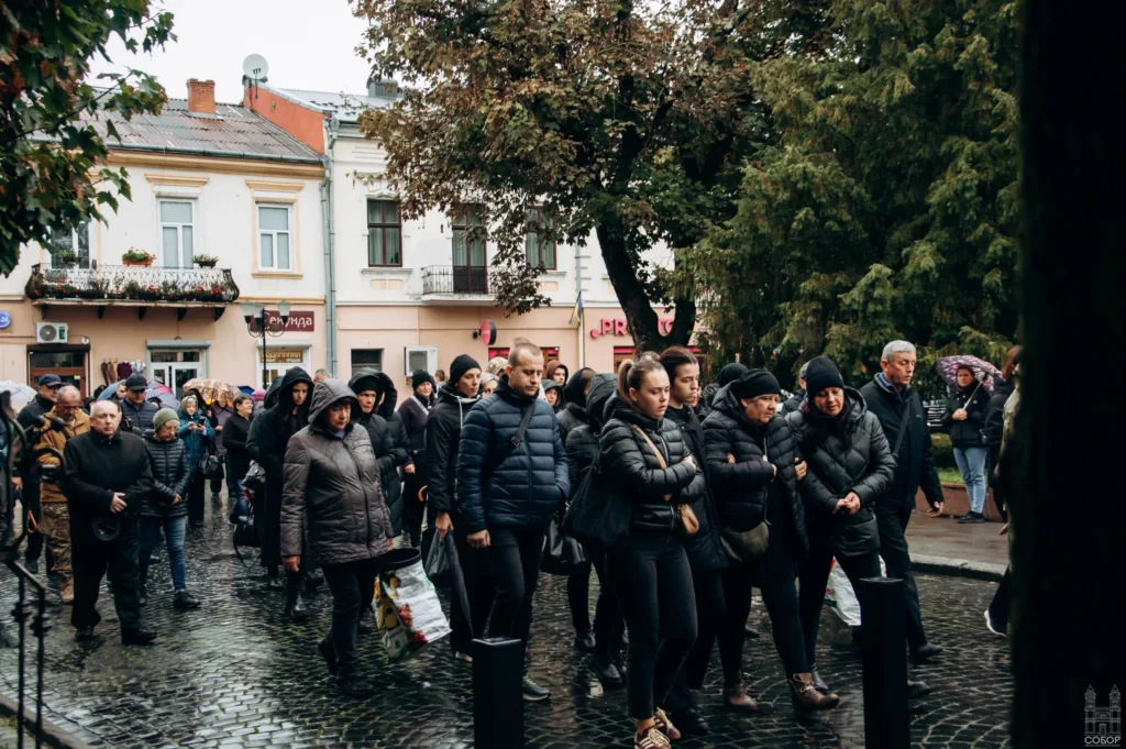 Люди йдуть під дощем вулицею міста