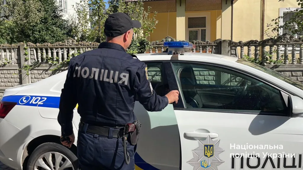 Поліцейський біля службового автомобіля поліції України