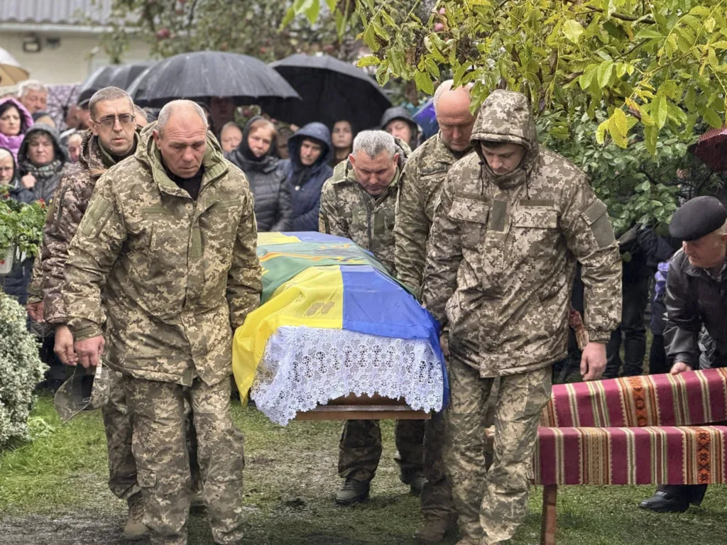 Військові несуть труну, накриту українським прапором