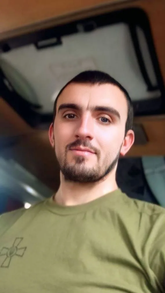 Чоловік у зеленій футболці сидить у приміщенні