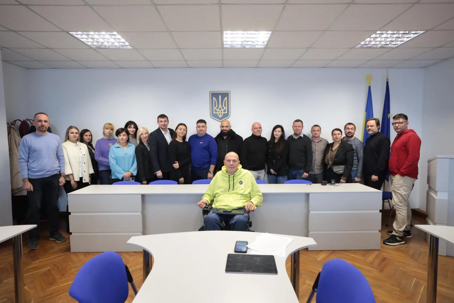 Група людей у залі з гербом України