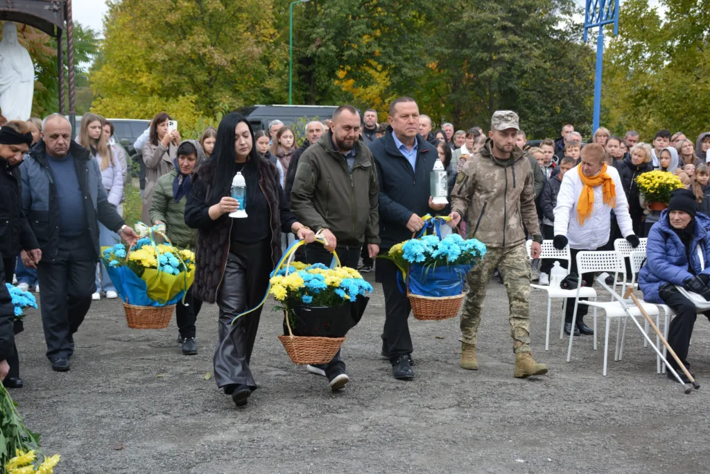 Люди несуть квіти на урочистій церемонії пам’яті