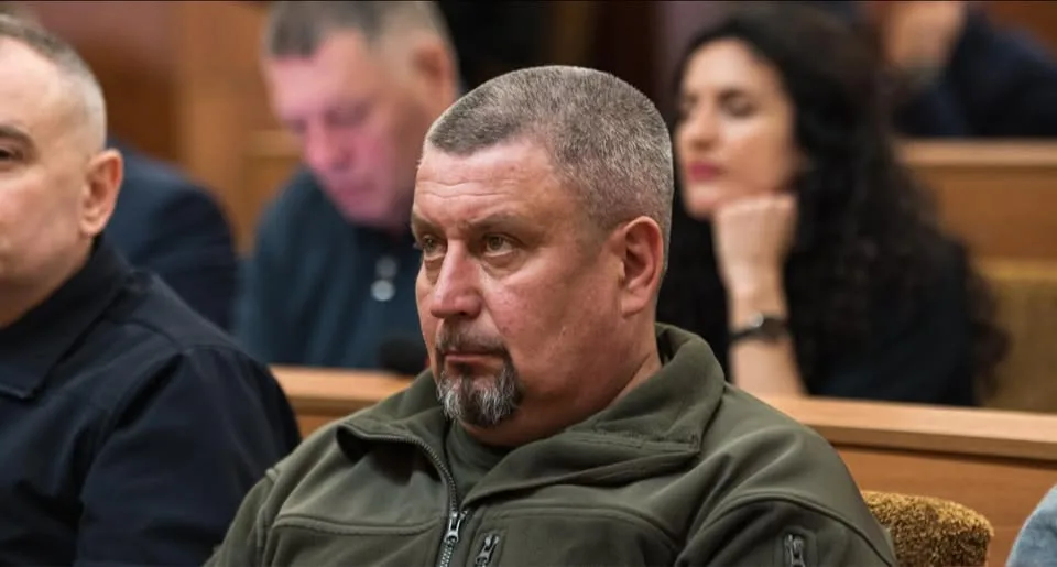 Чоловік сидить у залі суду, люди позаду
