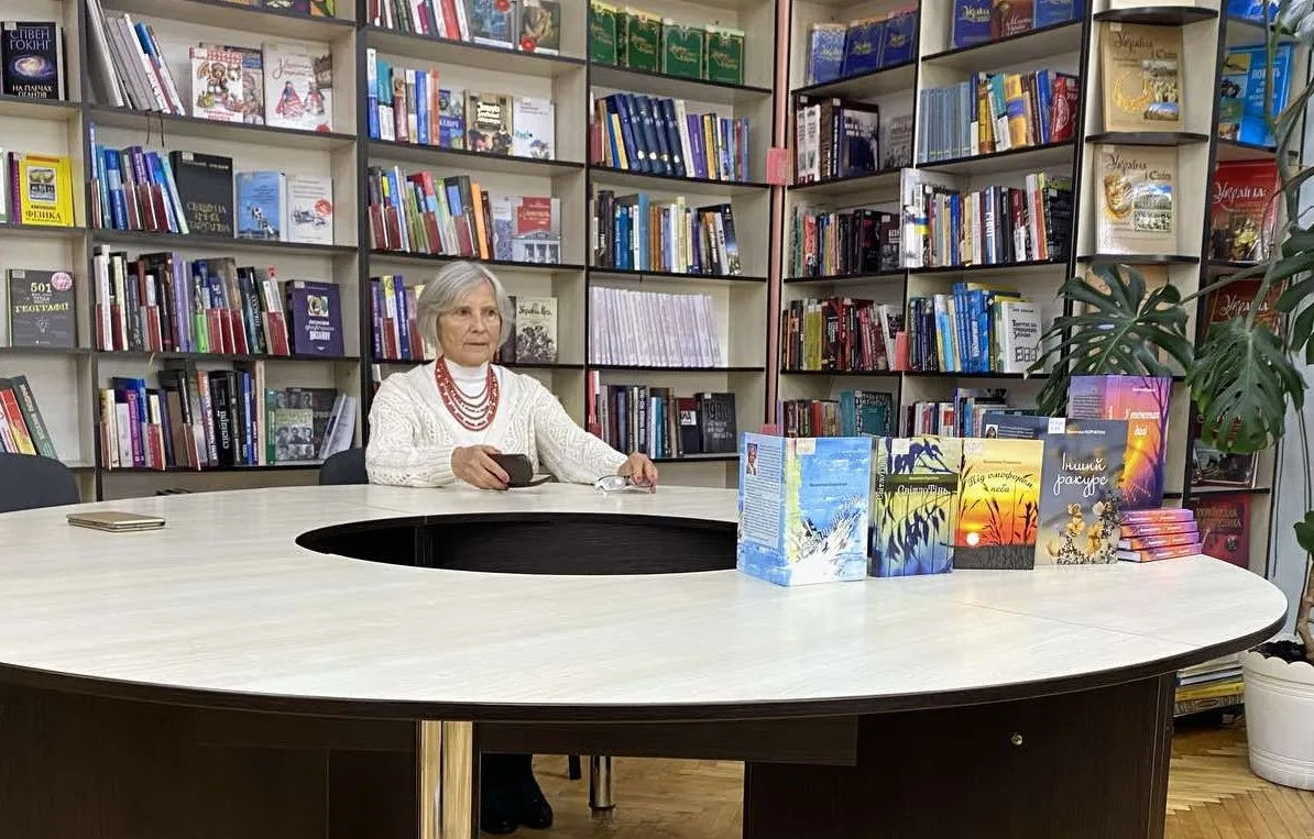 Жінка у бібліотеці з книжками на столі