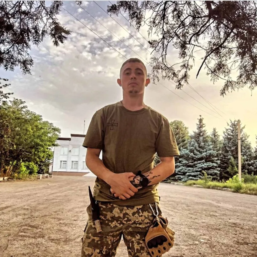 Військовий стоїть на вулиці біля дерев