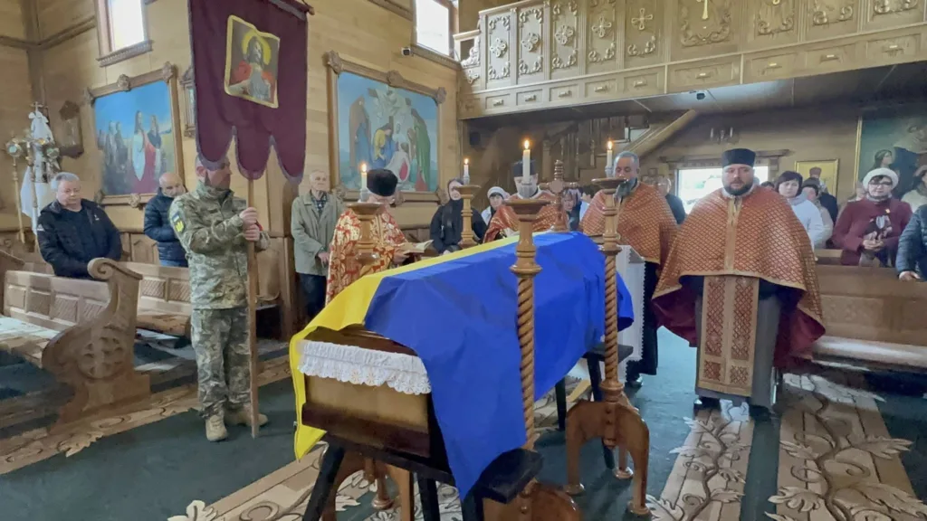 Похоронна церемонія в церкві з українським прапором