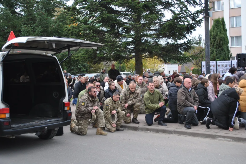 Люди та військові стоять на колінах під час церемонії