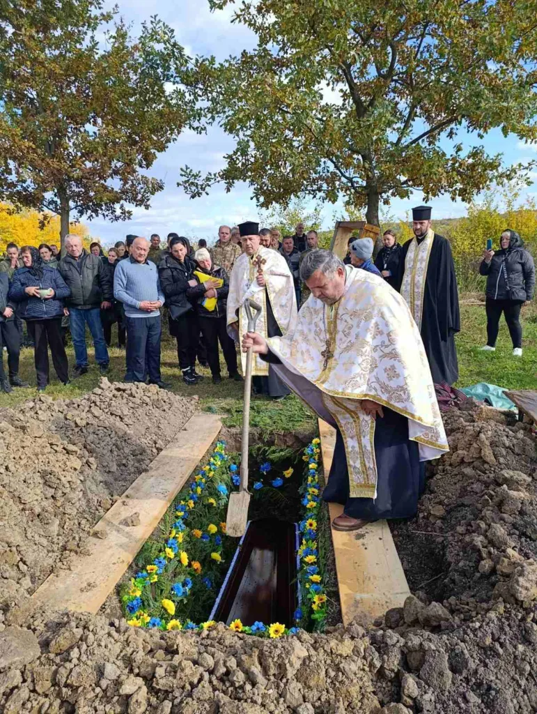 Священник проводить похоронну церемонію на кладовищі