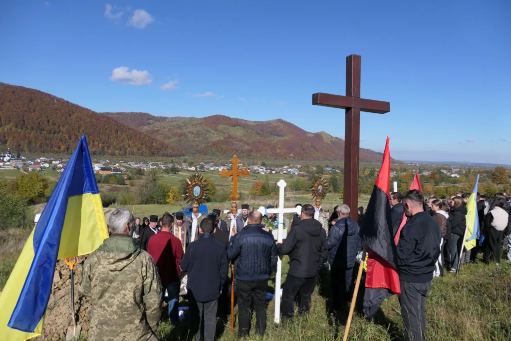 Люди з прапорами на церемонії в українських горах