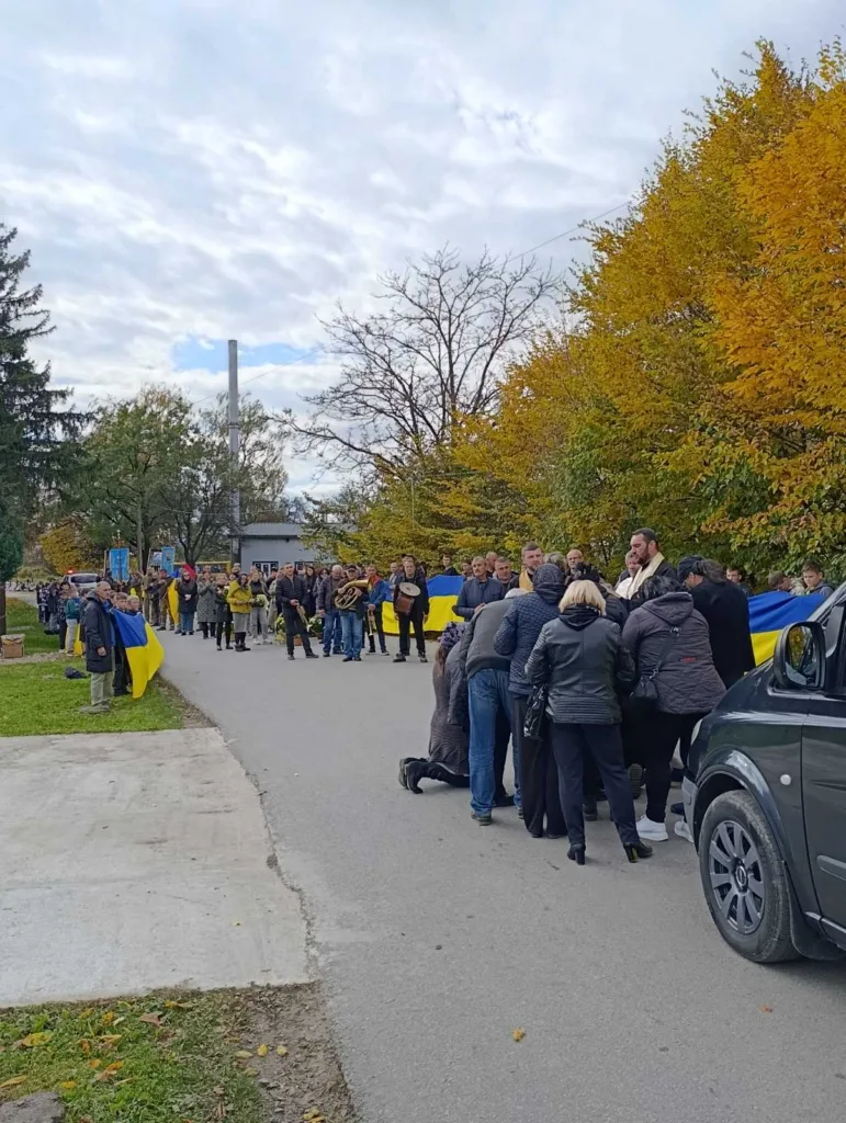Люди з українськими прапорами на вулиці восени