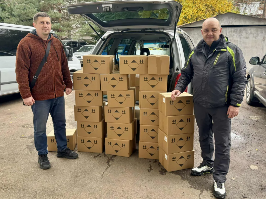 Двоє чоловіків із коробками гуманітарної допомоги біля авто