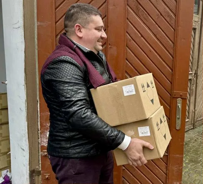 Чоловік несе дві картонні коробки до дверей