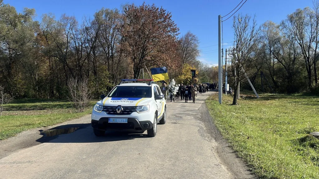Поліцейський автомобіль веде ходу з українським прапором