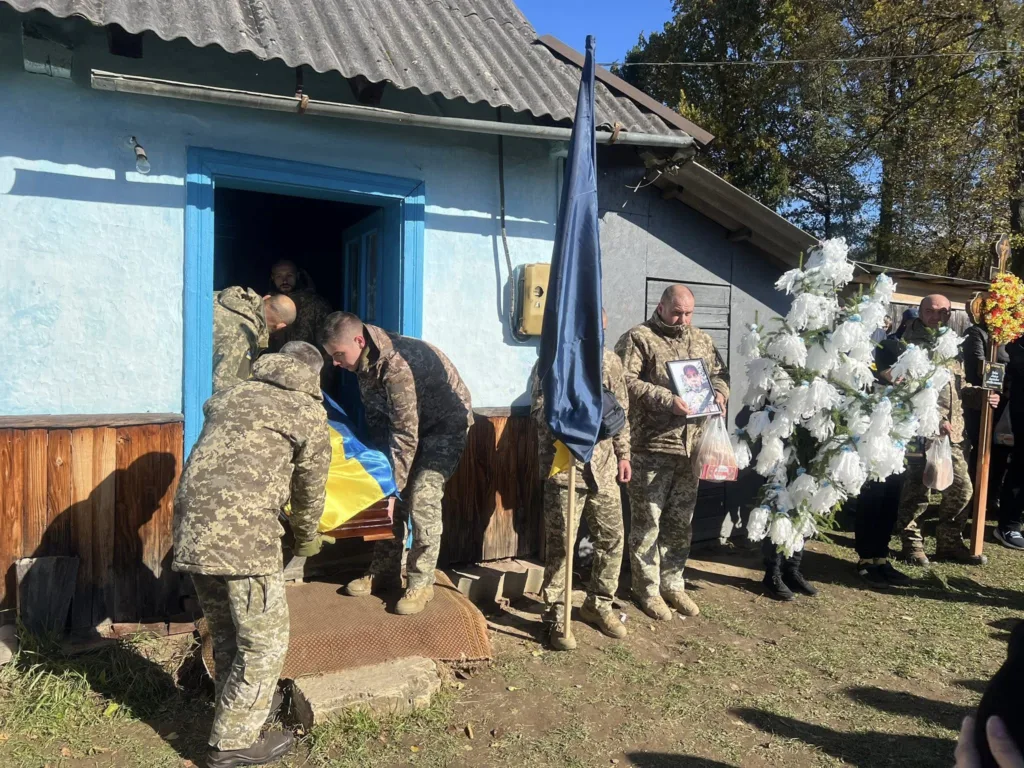 Військові несуть труну, накриту українським прапором