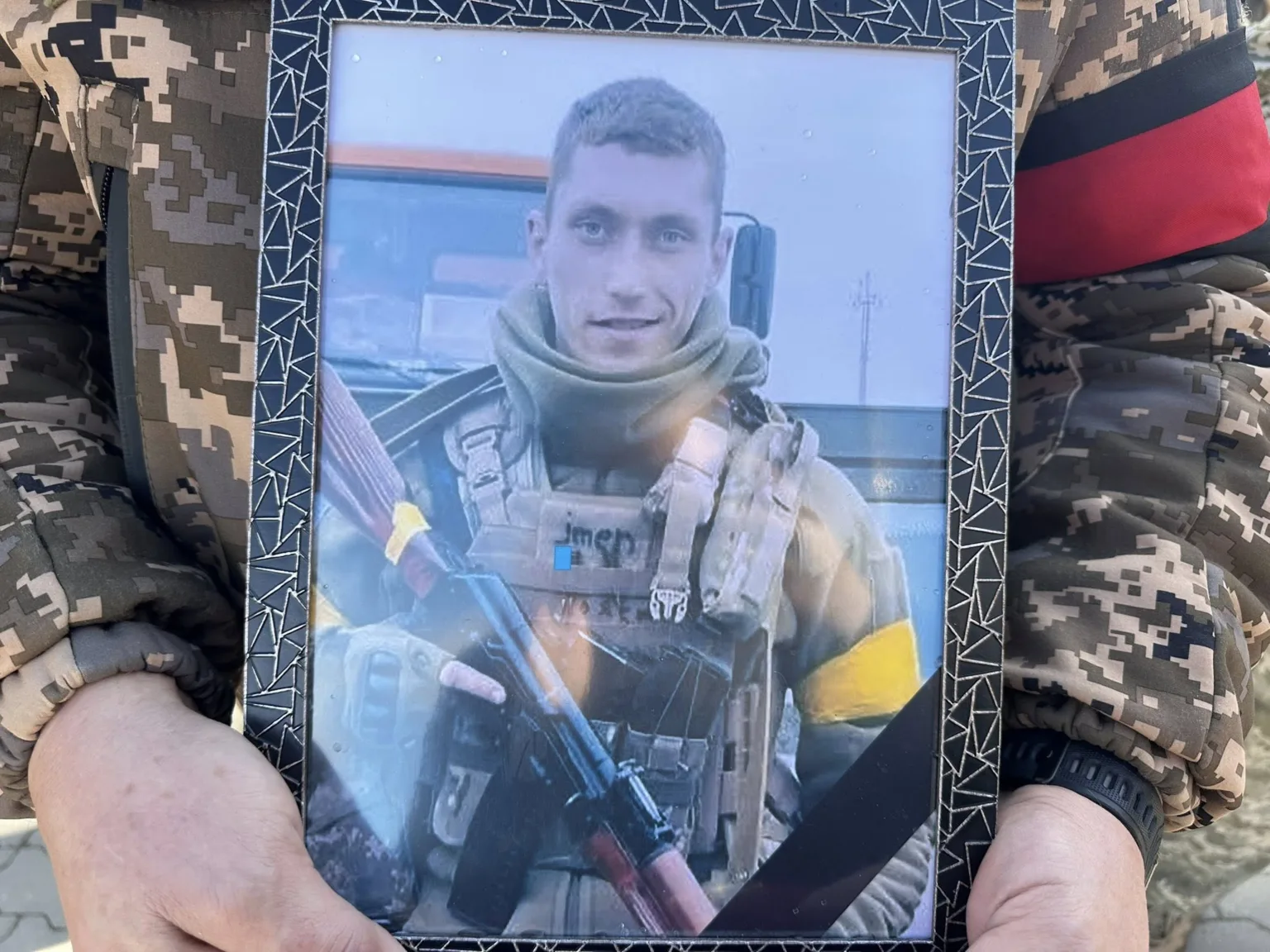 Військовий у камуфляжі тримає фото солдата