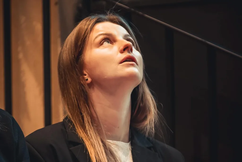 Жінка в піджаку дивиться вгору